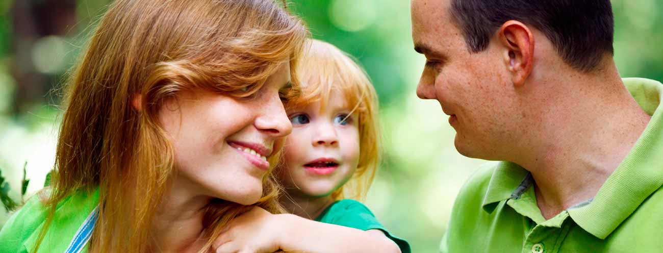 I genitori con una bimba dai capelli rossi aulle spalle