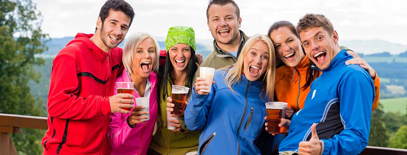 Friends with glass of beer in hand while laughing into the camera