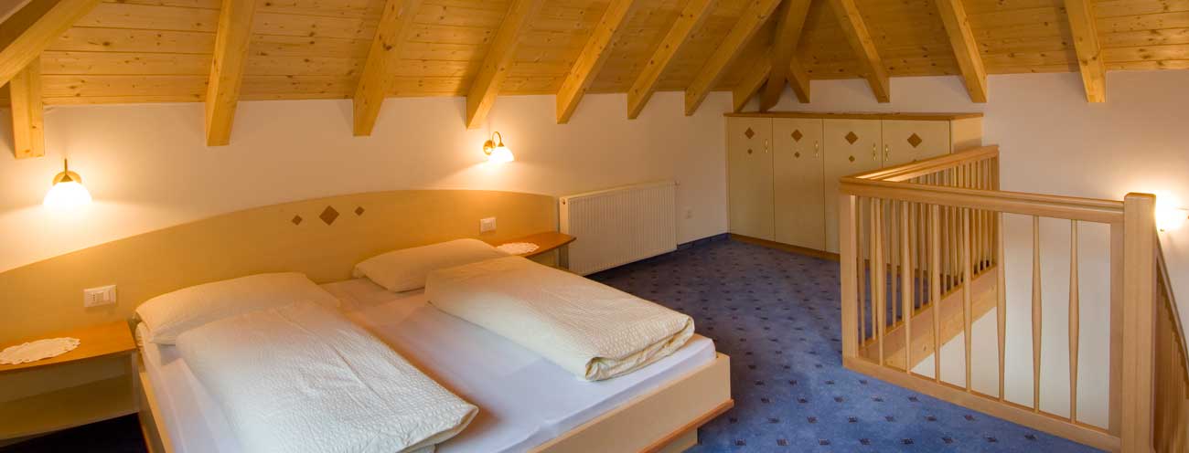 Mansarden-Zimmer aus natürlichem, hellem Holz mit Doppelbett