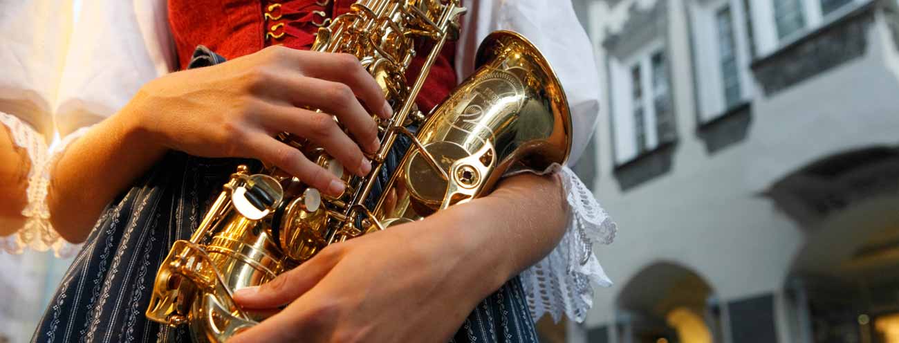 Eine Frau in typischer Tracht in Südtirol mit einem Saxophon in den Händen