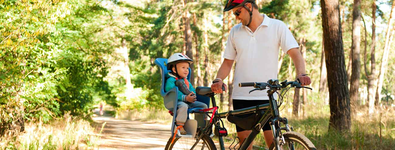 Vater mit kleinem Sohn in einem Kindersitz auf dem Fahrrad